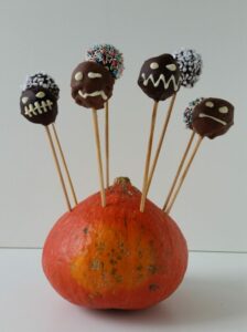 cake pops al cioccolato decorati per halloween infiliati in una zucca hokkaido